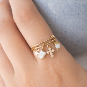 Bague ajustable à breloques en nacre Léa portée à la main avec étoile, trèfle et croix perlée