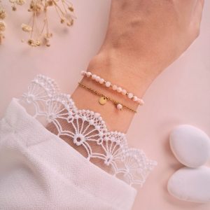 Bracelet Daphné double rang en opale rose porté au poignet avec médaille ronde dorée