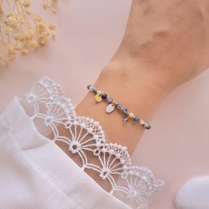 Bracelet en jaspe bleu et nacre Charlotte porté au poignet avec breloques dorées