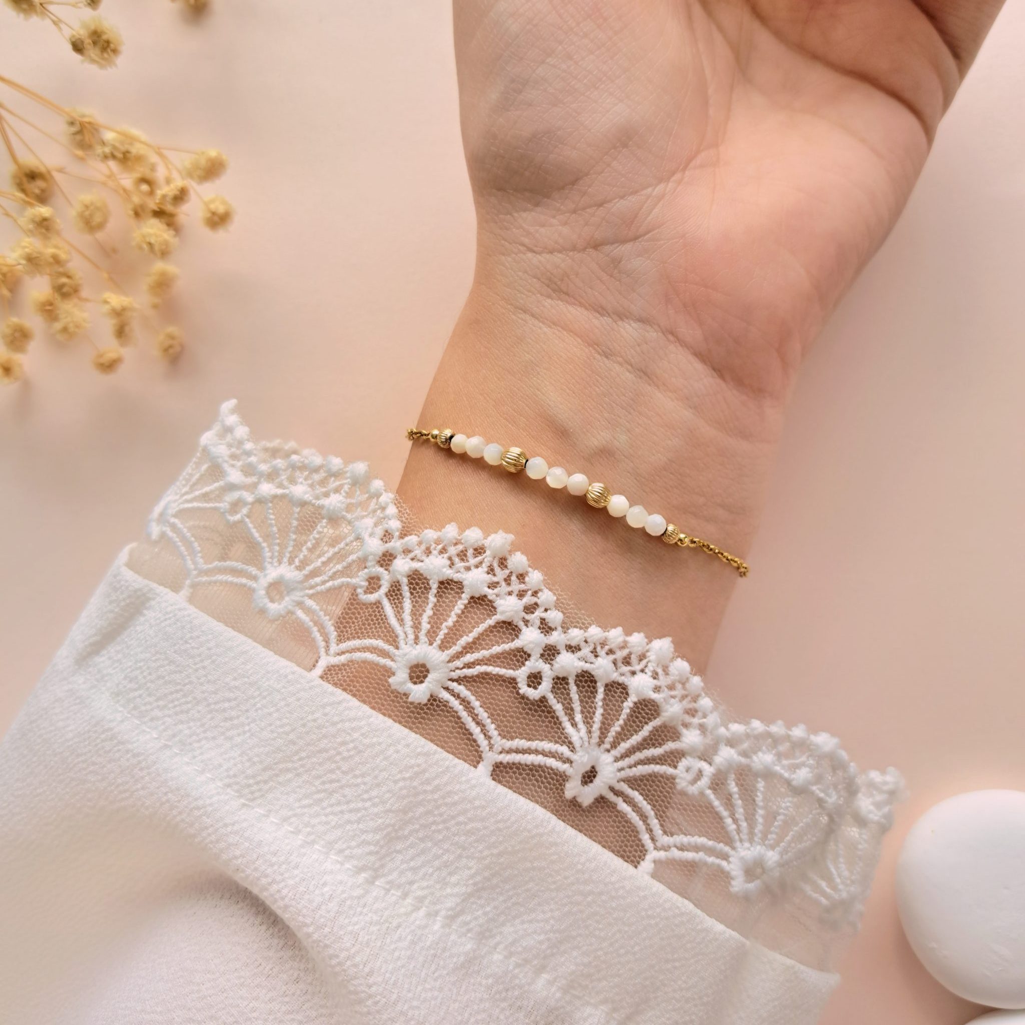 Bracelet nacre perles dorées Gabrielle n°2 porté sur l’intérieur du poignet avec détails dorés texturés