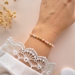 Bracelet Lina n°1 en opale rose pour femme porté au poignet avec détails dorés