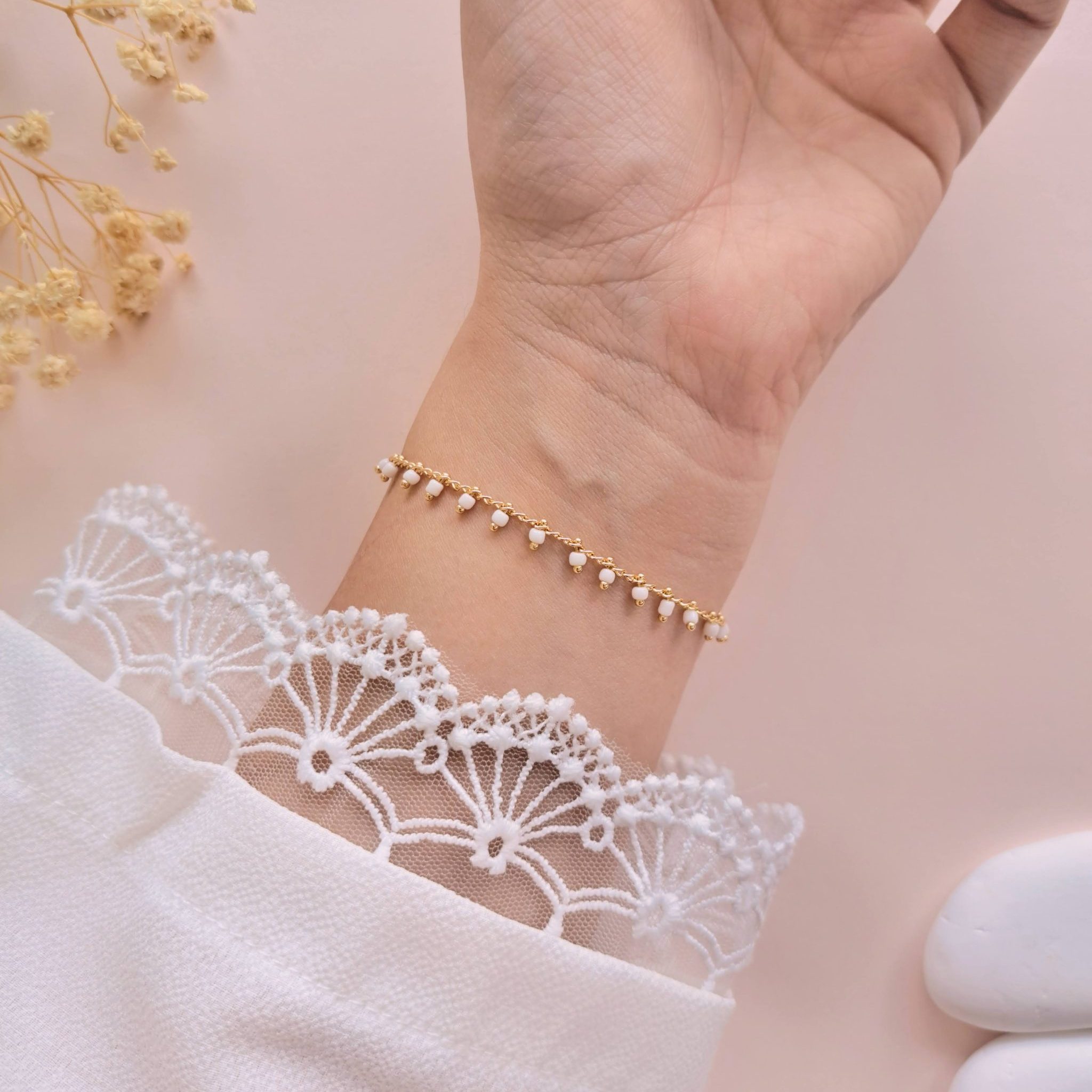 Bracelet perles blanches acier inoxydable Lily porté sur l’intérieur du poignet avec chaîne dorée