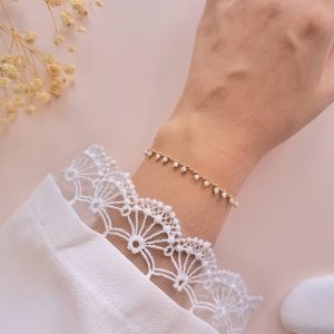 Bracelet perles blanches acier inoxydable Lily porté au poignet avec chaîne dorée délicate