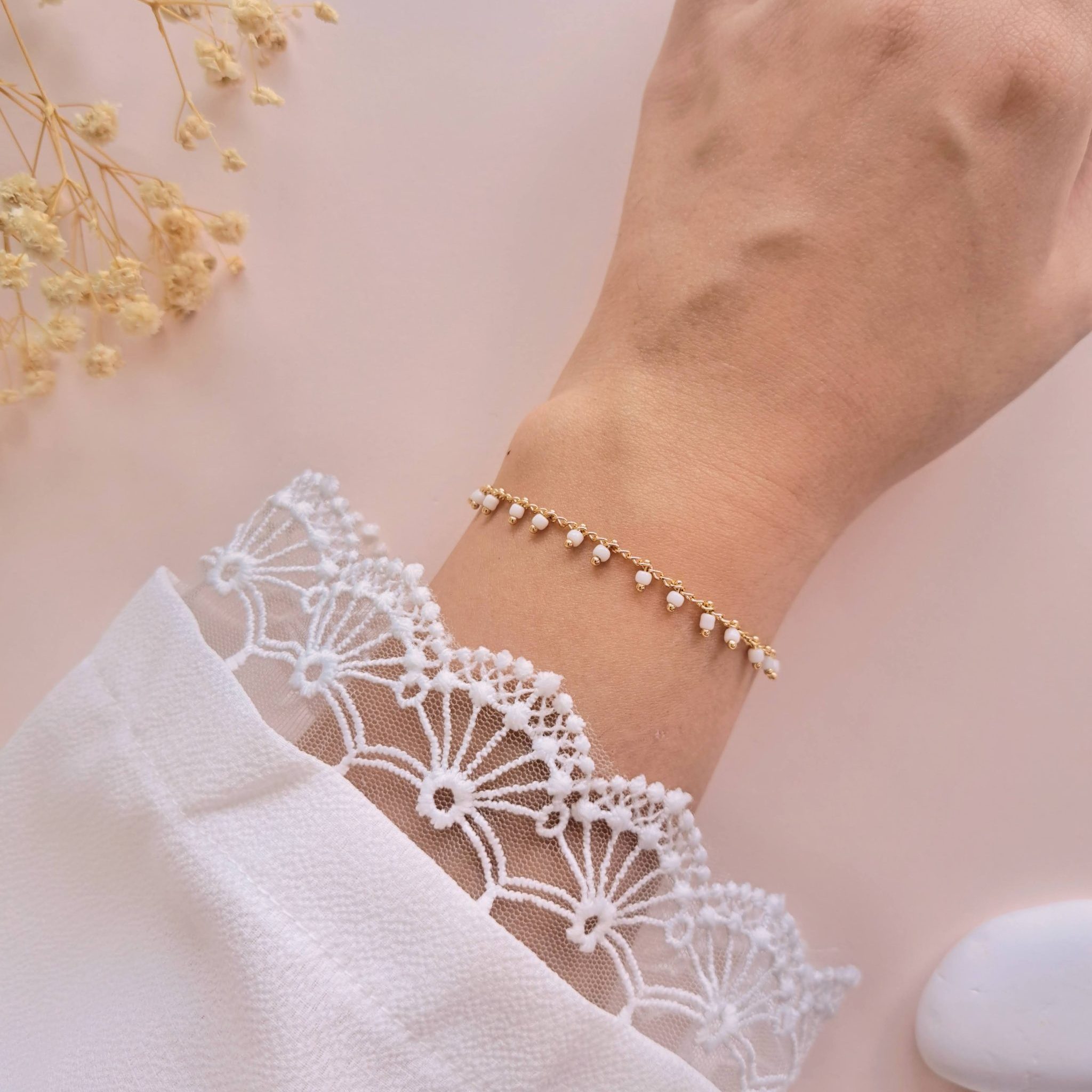 Bracelet perles blanches acier inoxydable Lily porté au poignet avec chaîne dorée délicate