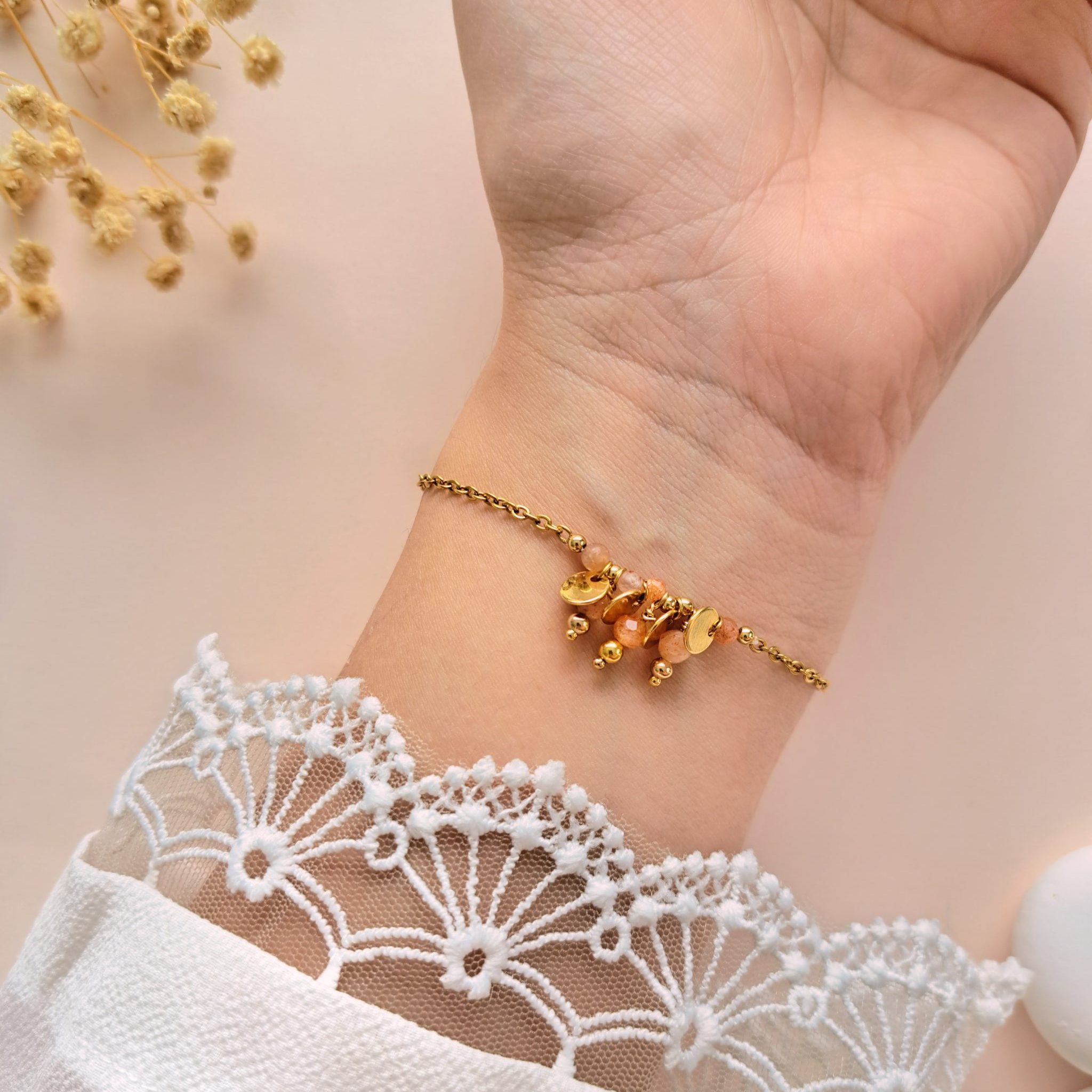 Bracelet pierre de soleil à breloques Eva n°3 porté sur l’intérieur du poignet avec breloques rondes en cuivre doré