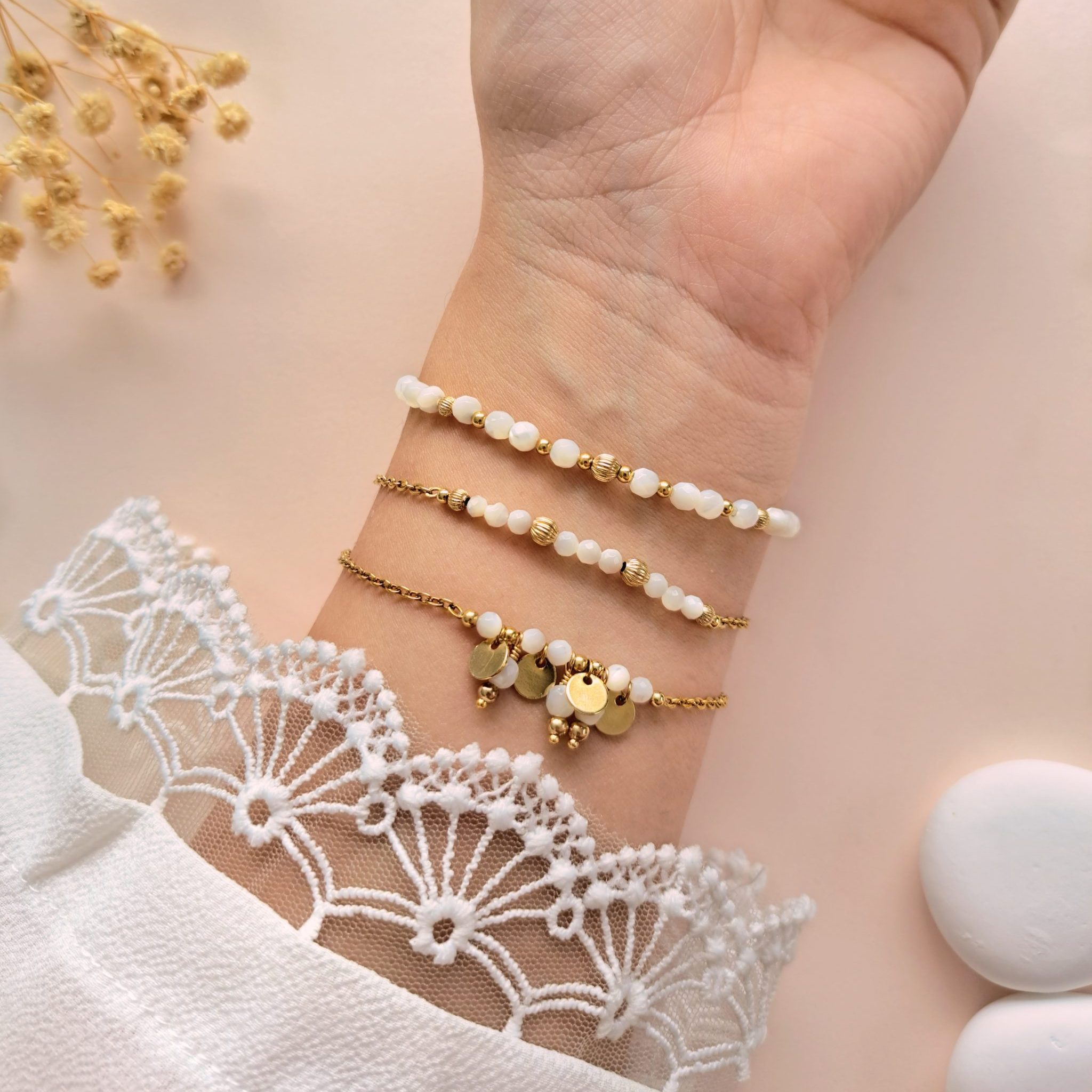 Ensemble de bracelets en nacre Trio Gabrielle porté sur l’intérieur du poignet avec breloques dorées