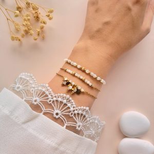 Ensemble de bracelets en nacre Trio Gabrielle porté au poignet avec détails dorés et breloques rondes