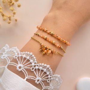 Ensemble de bracelets pierre de soleil Trio Eva porté au poignet avec détails dorés et breloques rondes