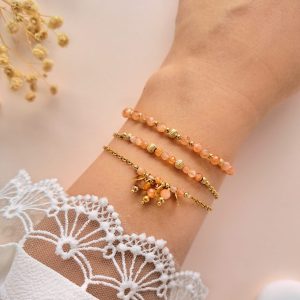 Ensemble de bracelets pierre de soleil Trio Eva porté au poignet avec détails dorés et breloques rondes