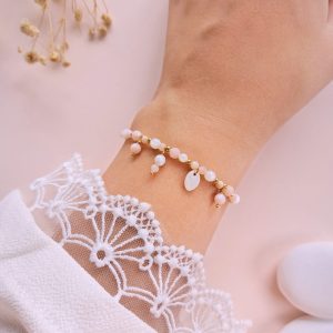 Bracelet Juliette en opale rose à breloques porté au poignet avec détails en nacre et dorés