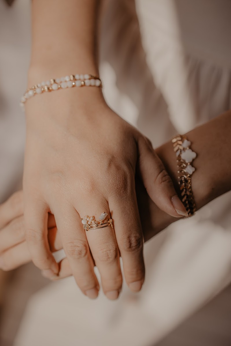 Main portant une bague dorée et des bracelets Soleva en pierres naturelles
